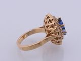 a close up of a gold ring with a blue sapphire and diamonds