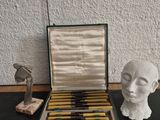 an open box of pens sitting on top of a table next to a statue of a head