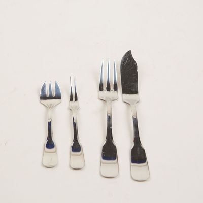 quatre fourchettes et un couteau posés sur un plan de travail blanc