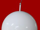 Le grand luminaire blanc est accroché au mur rouge.