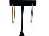a pair of gold hoop earrings on a black stand