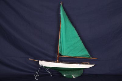 un petit voilier avec une voile verte posé sur une table