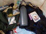 a bag of clothing and a bottle of water on the bed