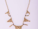 a gold necklace with blue stones on a white background