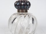 une bouteille en verre avec un bouchon métallique posée sur une surface blanche