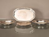 trois plats en argent posés sur une table en verre