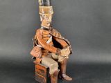 an old wooden toy soldier sitting on a chair with a hat on his head