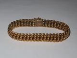 a close up of a gold bracelet on a white surface