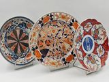 three decorative plates with designs on them on a white surface