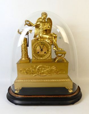 une horloge en or sous un dôme de verre sur une table