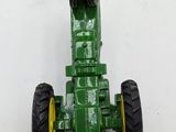 a green toy tractor that is sitting on a white surface