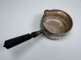 a silver cup with a black handle on a white table