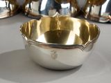 a silver bowl sitting on a table in front of other silver dishes