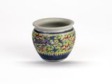 un petit vase bleu et jaune posé sur une surface blanche