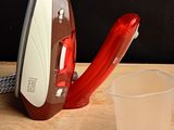 a red and white iron sitting on a table next to a cup of water