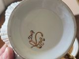 a person holding a white cup with a gold monogram on it