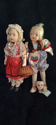 two dolls that are standing next to each other on a black background