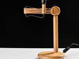 a close up of a wooden desk lamp on a white surface