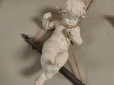 une statue représentant un Cupidon tenant un arc et un stylo, posée sur une table