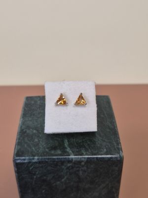 une paire de boucles d'oreilles en or posée sur un bloc de marbre