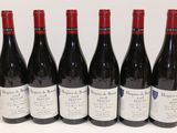 six bottles of red wine are lined up on a table