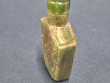 a small bottle with a green top sitting on a table