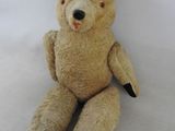 un ours en peluche assis sur une surface blanche