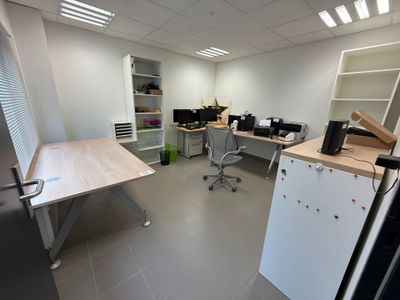 une photo d'une pièce avec un bureau et un réfrigérateur