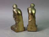 pair of bronze figurines of a man and woman sitting on a rock