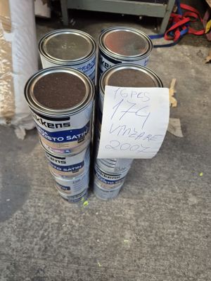 trois pots de peinture posés par terre à côté d'un panneau