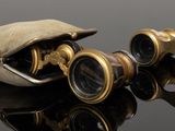 two pairs of binoculars are sitting next to each other on a reflective surface
