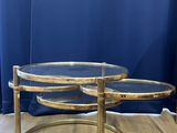 a pair of brass coffee tables with glass tops on a wooden floor