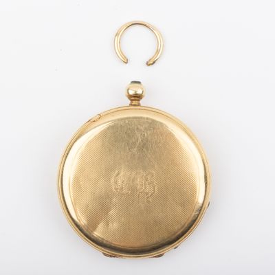 a close up of a gold pocket watch on a white surface