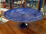 un plat à gâteau en verre bleu posé sur une table en bois