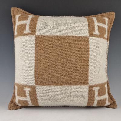 un coussin en laine à carreaux marron et blancs sur fond gris