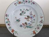 a white plate with colorful flowers on it on a stand