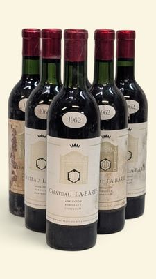 six bouteilles de vin sont alignées sur une surface blanche
