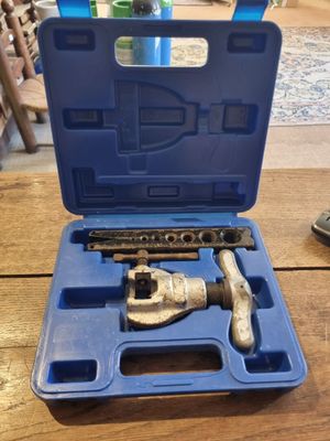 un ensemble d'outils rangé dans une mallette bleue posée sur une table en bois