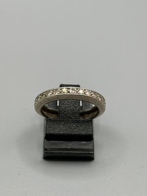 un gros plan d'une bague posée sur un support noir, sur une surface blanche