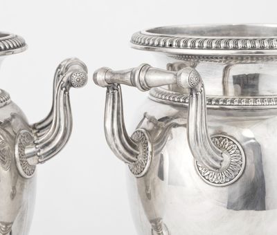 two silver vases with handles on each of them