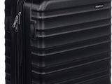 La valise noire repose sur ses roulettes, posée sur une surface blanche.