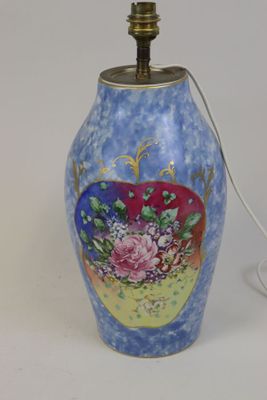 un vase bleu orné de fleurs, sur lequel est posée une lampe allumée