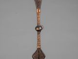 a wooden sculpture of a spear with a feather on it