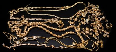 Plusieurs colliers et bracelets en or sont disposés sur une surface noire