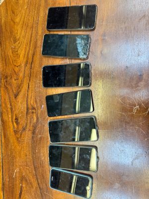 Plusieurs téléphones portables sont alignés sur une table en bois