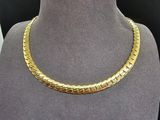 un collier en or sur un mannequin dans une vitrine de magasin