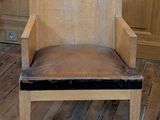 a wooden chair with a leather seat in the corner of a room
