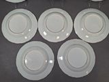 six white plates with gold rims are arranged on a table