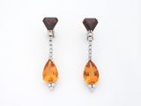 une photo d'une paire de boucles d'oreilles en saphir orange et diamants
