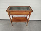 a small wooden table with a glass top on a cement floor